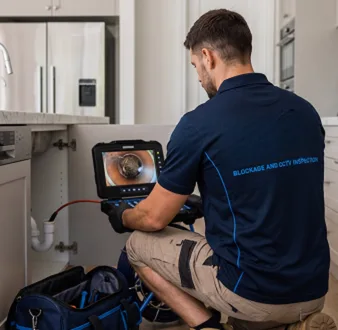 Plumber clearing a blocked toilet in a Allawah bathroom